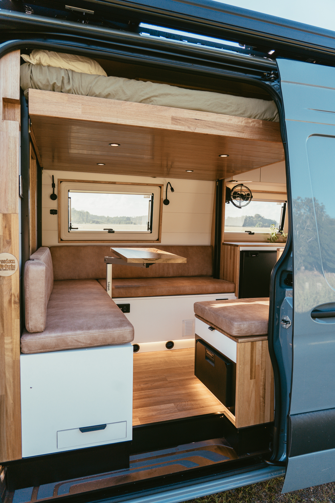 Sprinter camper dinette with slide-out table and Happijac bed lift above