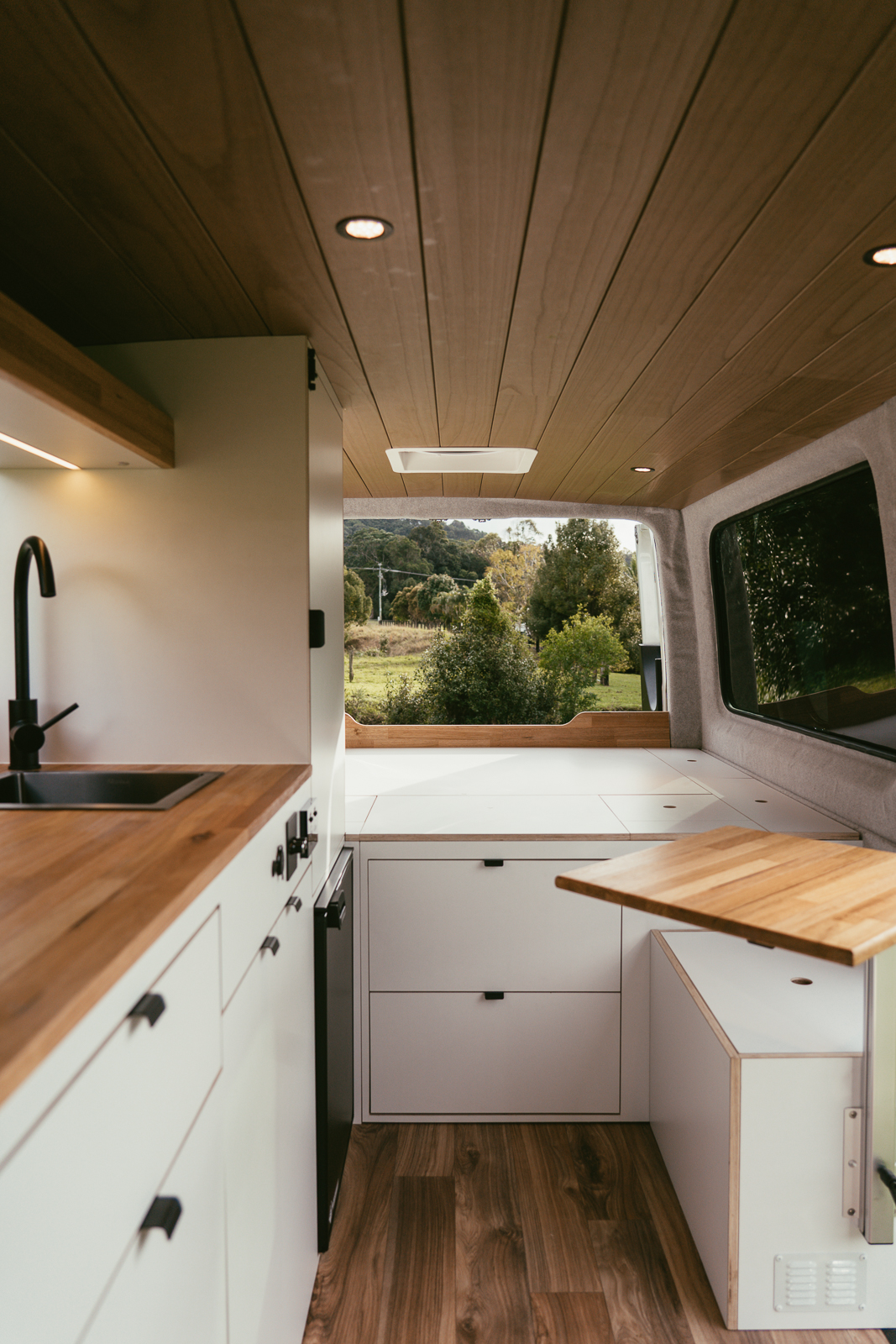 Custom camper van conversion interior with timber ceiling, kitchen and slide-out table